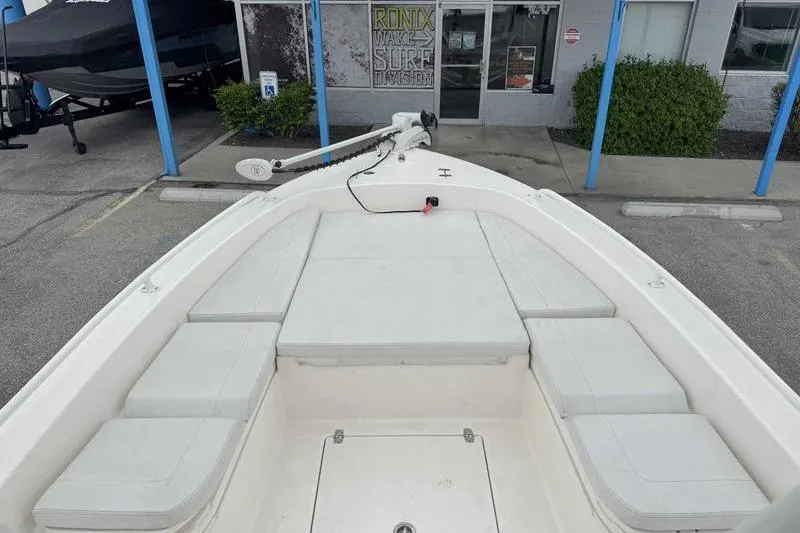 Slide: The Image of 2023 Pathfinder 2600 HPS boat deck with cushioned seating, parked outside a surf shop. - 4