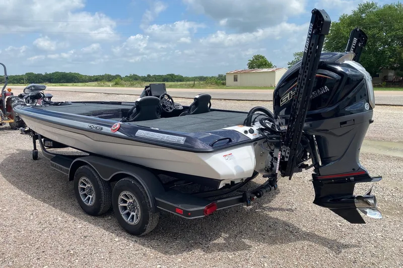 Slide: The Image of 2026 Skeeter ZXE20 bass boat with Yamaha engine, parked on gravel under a cloudy sky. - 4