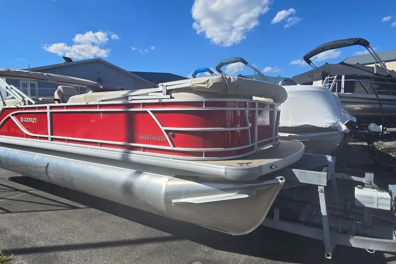 The Image of 2025 Godfrey Sweetwater 2286 SB pontoon boat with red exterior on a trailer. - 0