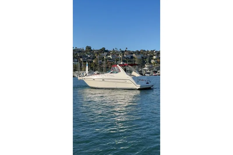 Slide: The Image of 1998 Maxum 3700 SCR yacht on calm water with scenic marina backdrop. - 2