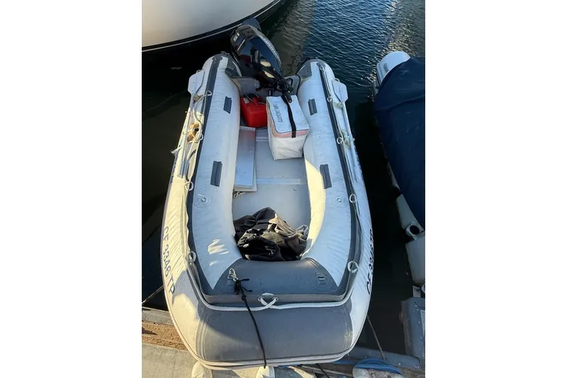 Slide: The Image of Inflatable dinghy docked beside a Maxum 3700 SCR, 1998 model, with outboard motor. - 27