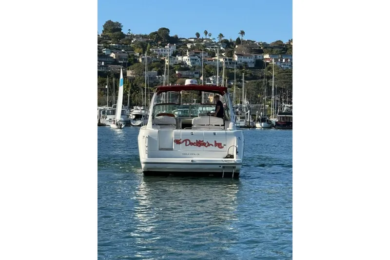 Slide: The Image of 1998 Maxum 3700 SCR boat on water, with marina and hillside homes in background. - 3