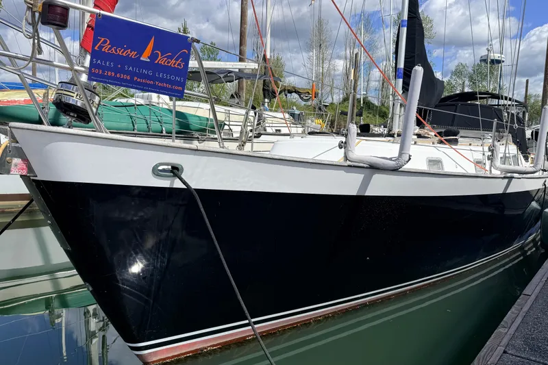 The Image of 1983 Tanton 44 sailboat docked, featuring "Passion Yachts" sales and sailing lessons banner. - 0