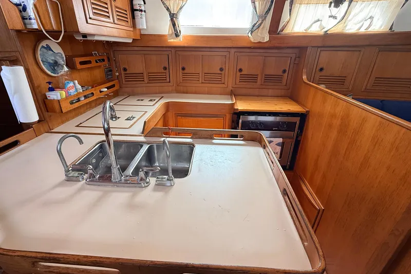 Slide: The Image of 1983 Tanton 44 yacht kitchen with wooden cabinetry, dual sink, and stove. - 13