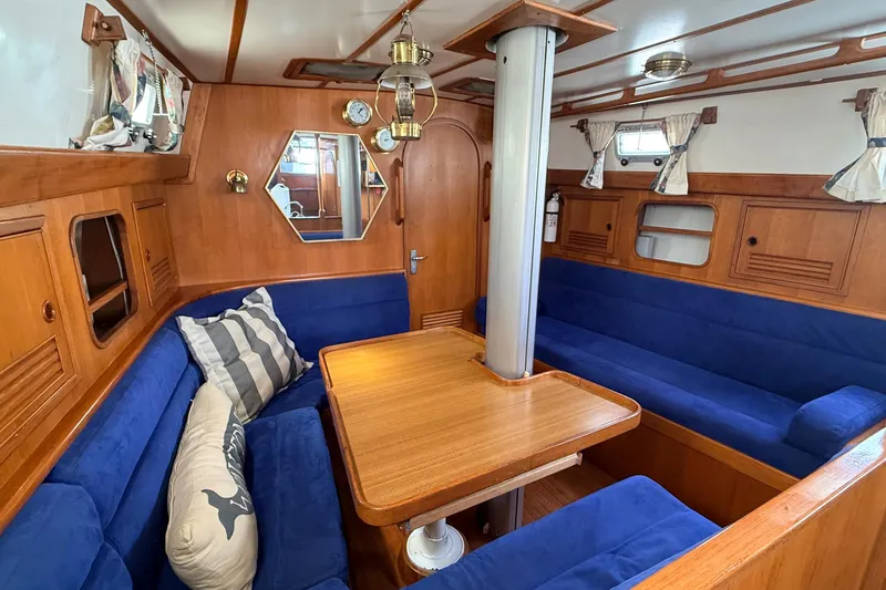 Slide: The Image of Cozy 1983 Tanton 44 yacht interior with blue seating, wooden table, and nautical decor. - 3