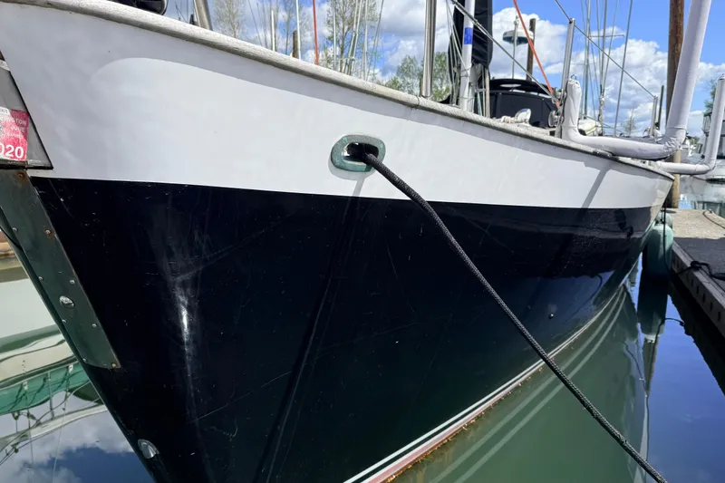 Slide: The Image of 1983 Tanton 44 sailboat docked, featuring a sleek black and white hull design. - 33