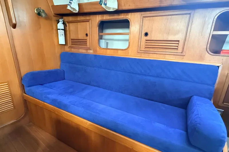 Slide: The Image of Blue cushioned seating in 1983 Tanton 44 yacht interior with wooden paneling. - 6