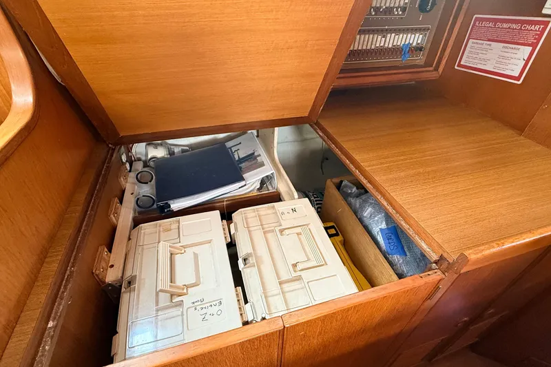 Slide: The Image of Storage compartment in a 1983 Tanton 44 sailboat, featuring organized tools and manuals. - 9