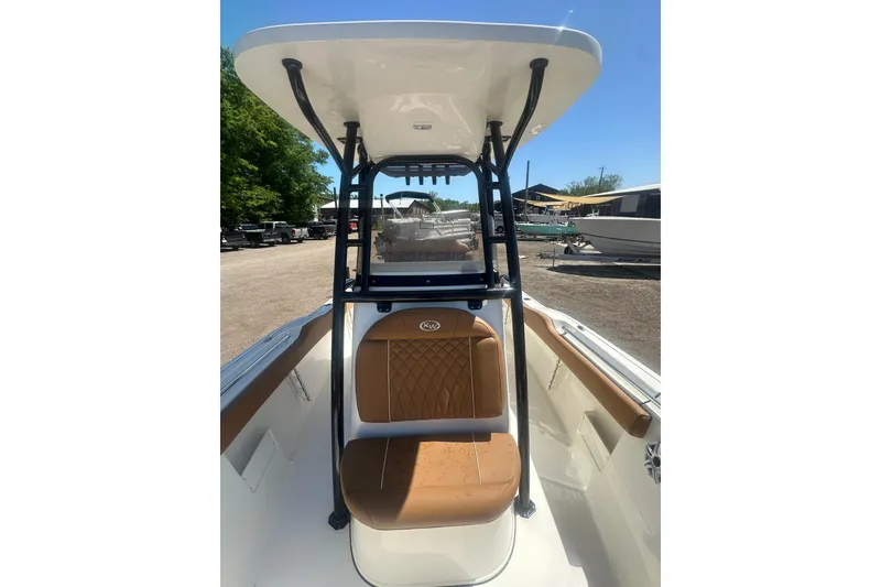 Slide: The Image of 2026 Key West 239 FS boat interior with tan seating and T-top, parked outdoors. - 28
