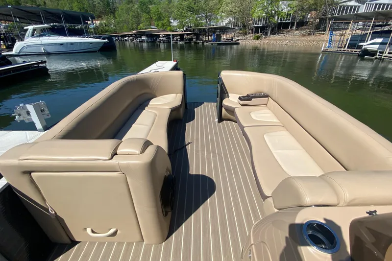 Slide: The Image of 2018 Harris Solstice 240 boat with beige seating on a striped deck by the water. - 22