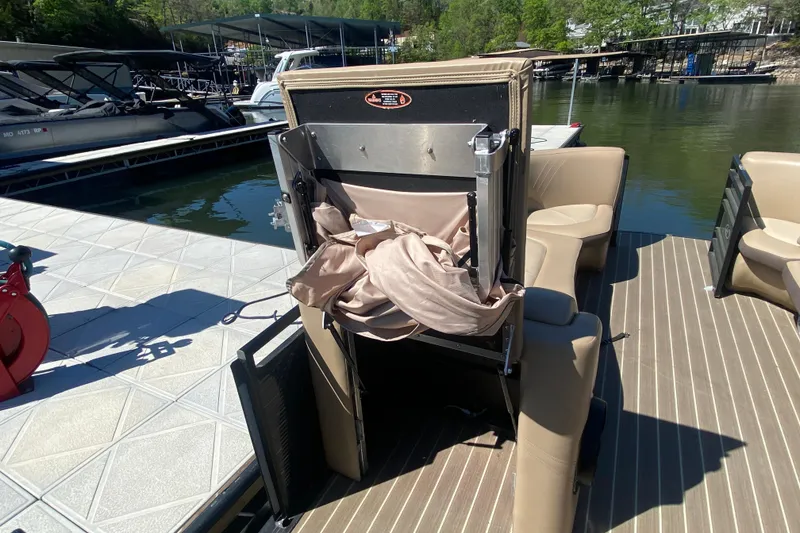 Slide: The Image of 2018 Harris Solstice 240 boat interior with beige seating and cup holders on a sunny day. - 24