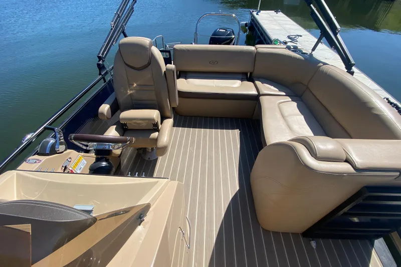 Slide: The Image of 2018 Harris Solstice 240 boat interior with beige seating and striped flooring at a dock. - 9