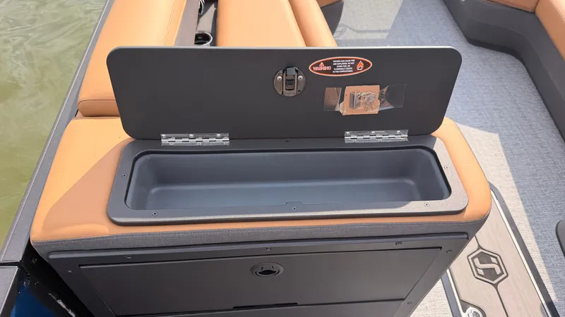Slide: The Image of A storage compartment on a Harris Sunliner 230 boat with beige upholstery and gray flooring. - 27