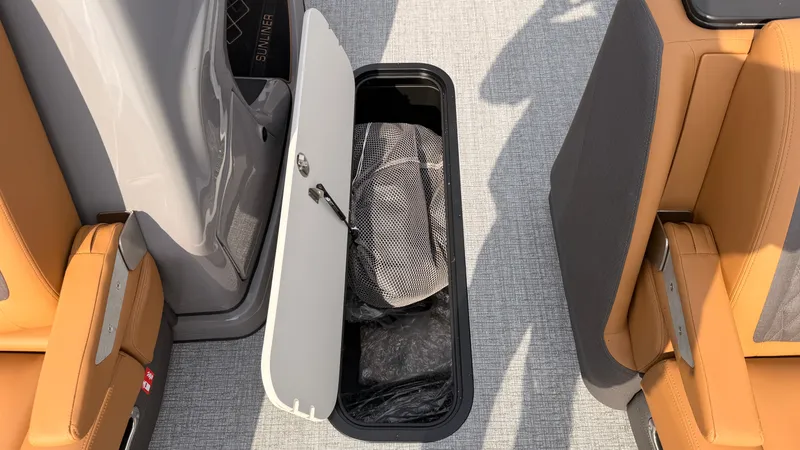 Slide: The Image of An open storage compartment on a boat with gray carpet and beige seats. - 24