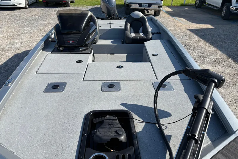 Slide: The Image of 2026 Vexus AVX181 boat interior with seating and motor, parked on gravel. - 7
