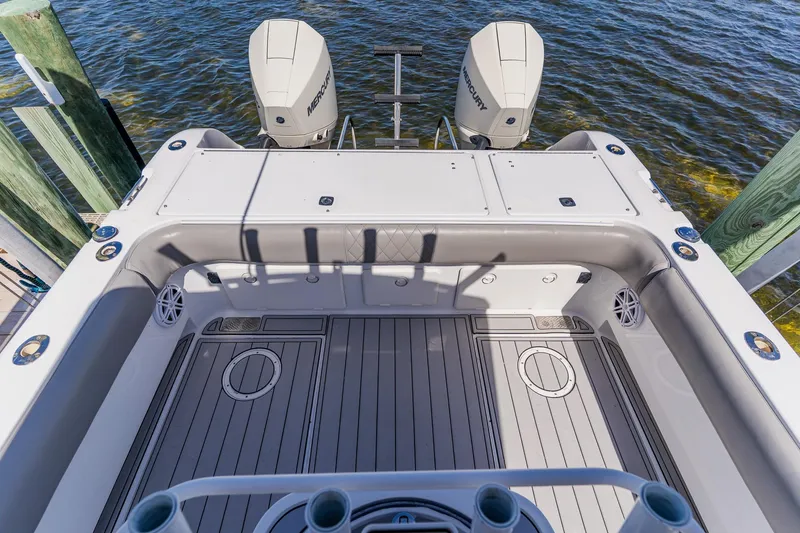 Slide: The Image of 1998 World Cat 266 SF boat deck with twin Mercury engines, docked by the water. - 26