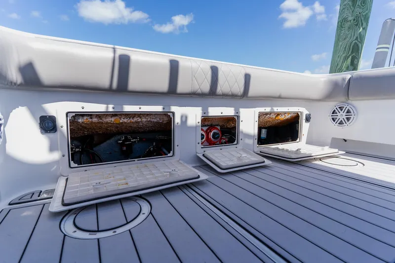 Slide: The Image of 1998 World Cat 266 SF boat deck with open storage compartments under clear blue sky. - 33