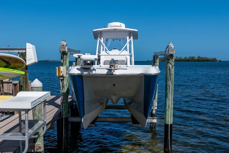 Slide: The Image of 1998 World Cat 266 SF boat on lift by dock, clear blue sky and water. - 4