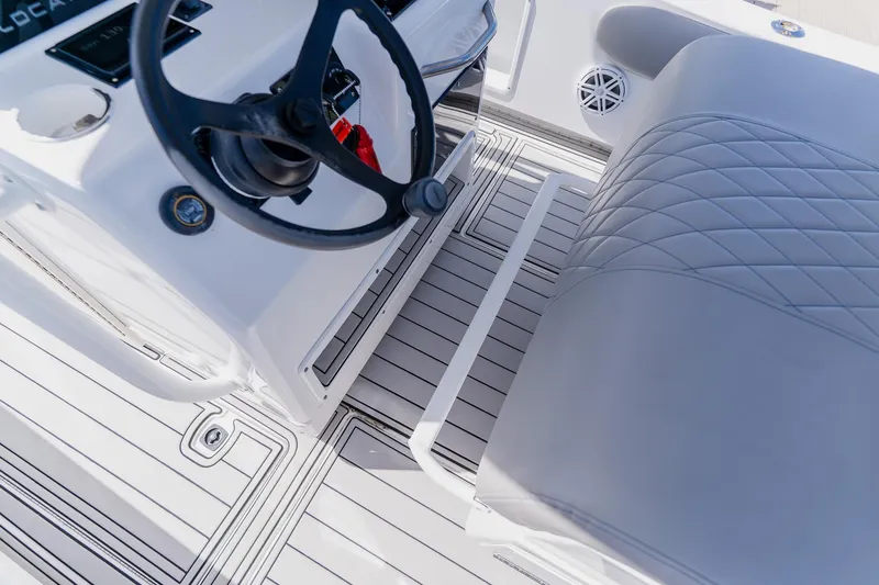Slide: The Image of Interior view of a 1998 World Cat 266 SF boat, featuring steering wheel and cushioned seating. - 52