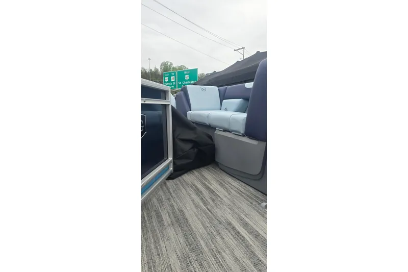 Slide: The Image of 2026 Godfrey Sweetwater 2286 SFL boat interior with blue seating and highway signs in background. - 2