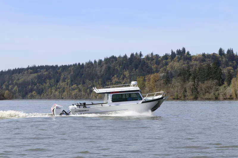 Slide: The Image of 2026 Alumaweld Horizon 26 boat cruising on a scenic river with forested background. - 2