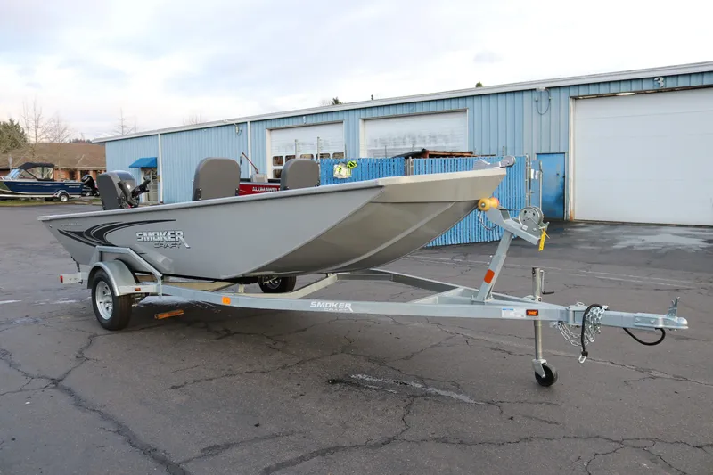 Slide: The Image of 2026 Smoker Craft Sportsman 1660 boat on trailer, parked outside industrial building. - 3