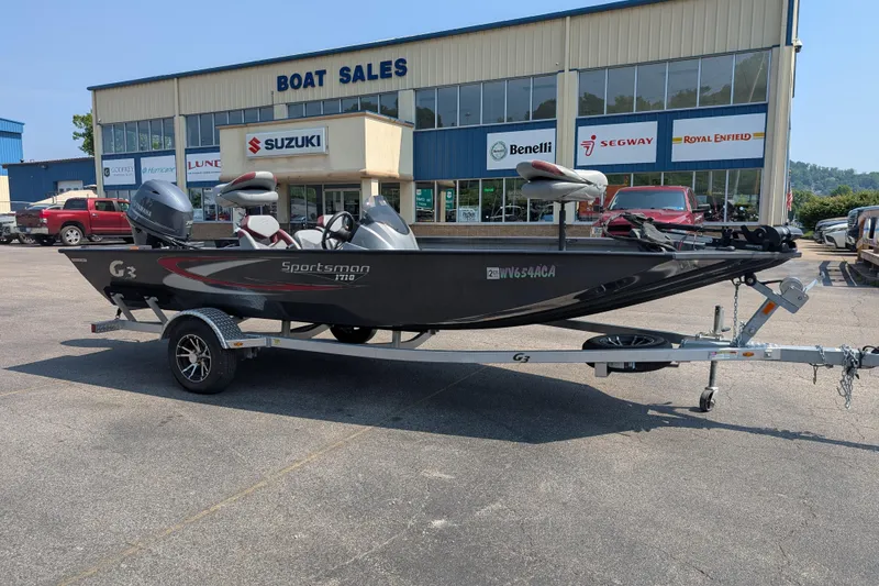 The Image of 2022 G3 Sportsman 1710 boat on trailer outside dealership, featuring Suzuki and Yamaha branding. - 0