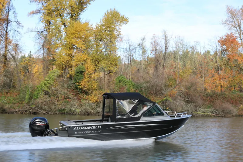 Slide: The Image of 2026 Alumaweld Stryker X202 boat cruising on a river with autumn foliage backdrop. - 2