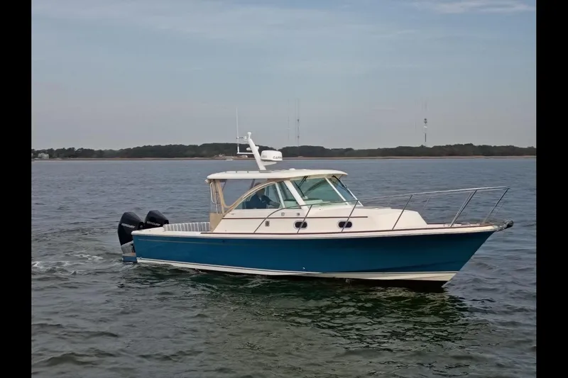 Slide: The Image of 2020 Hunt Yachts Surfhunter 32 docked in a marina, reflecting on calm water. - 2