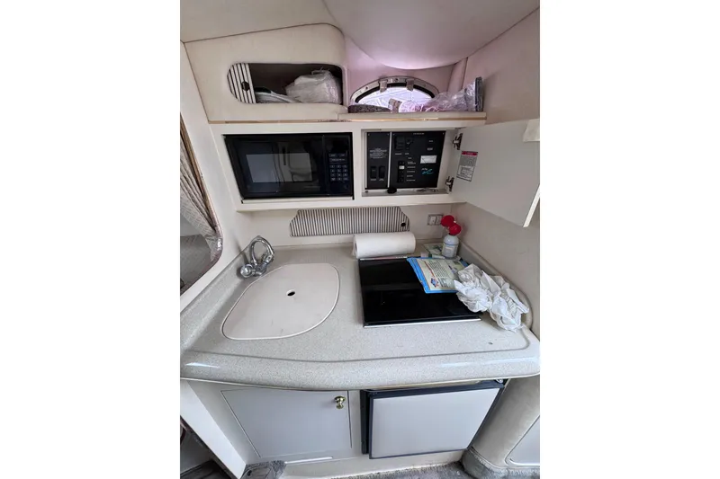 Slide: The Image of 1999 Sea Ray 270 Sundancer Special Edition boat kitchenette with sink, microwave, and storage. - 12