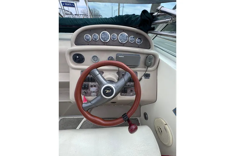 Slide: The Image of 1999 Sea Ray 270 Sundancer helm with gauges, steering wheel, and navigation equipment. - 8