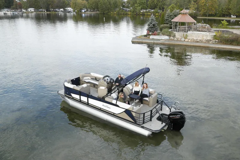 The Image of 2026 SunChaser Eclipse 25 LR DH pontoon boat on a serene lake with passengers. - 1
