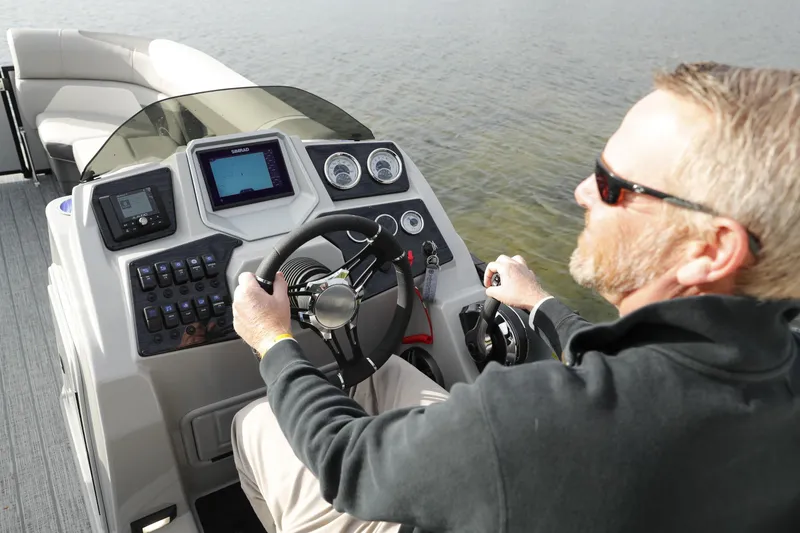 Slide: The Image of Man steering 2026 SunChaser Eclipse 25 LR DH pontoon boat on water. - 3