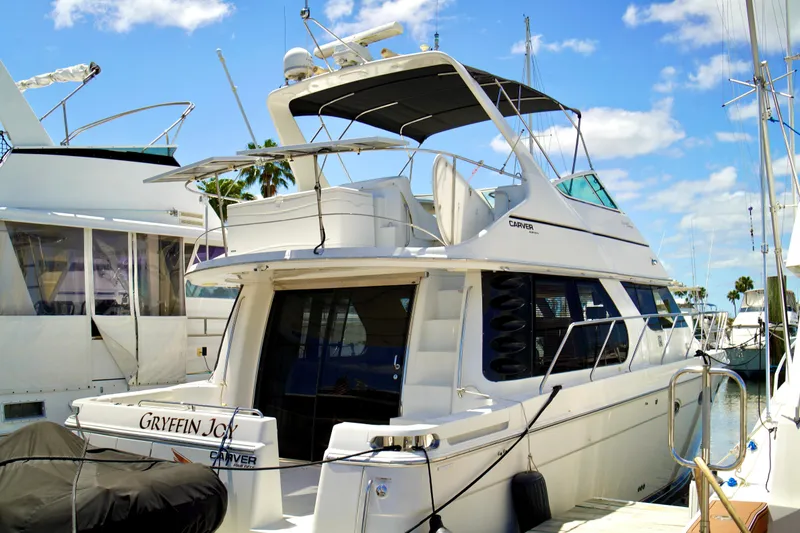The Image of 1999 Carver 450 Voyager Pilothouse yacht docked at marina under blue sky. - 0