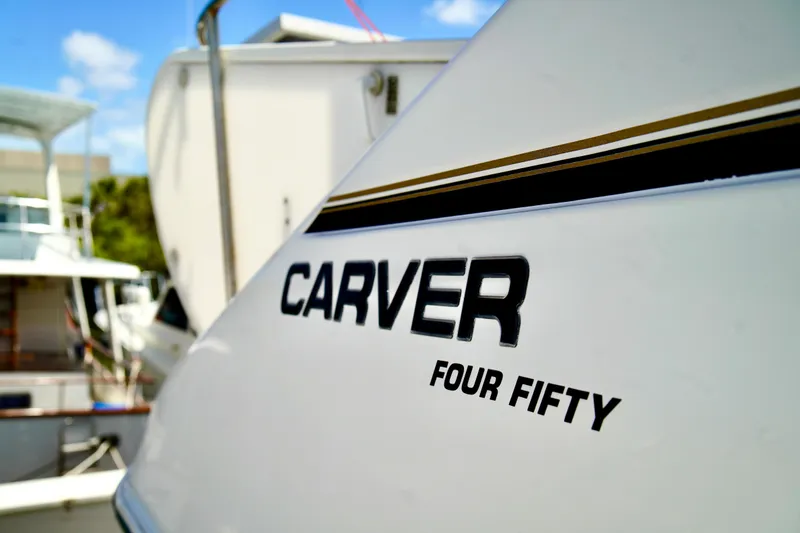 Slide: The Image of 1999 Carver 450 Voyager Pilothouse yacht docked, showcasing sleek design and branding. - 2