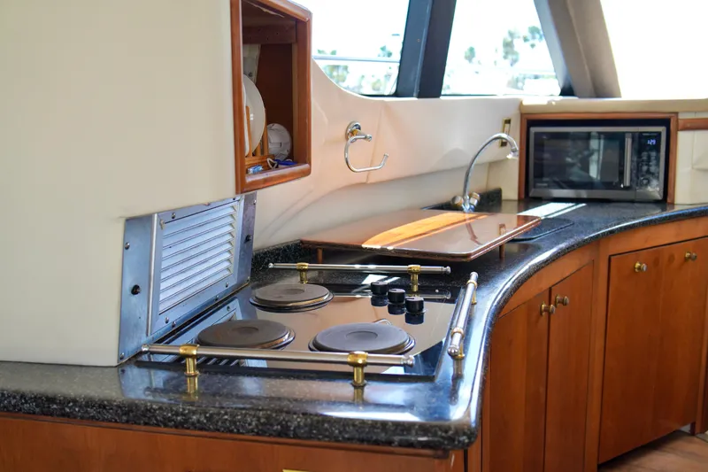 Slide: The Image of Interior of 1999 Carver 450 Voyager Pilothouse kitchen with stove, sink, and microwave. - 33