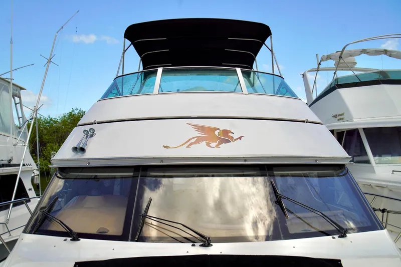Slide: The Image of 1999 Carver 450 Voyager Pilothouse yacht with distinctive emblem, docked between boats. - 4