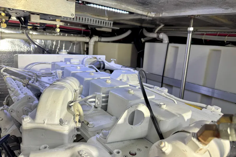 Slide: The Image of Engine room of 1999 Carver 450 Voyager Pilothouse, showcasing mechanical components and piping. - 52