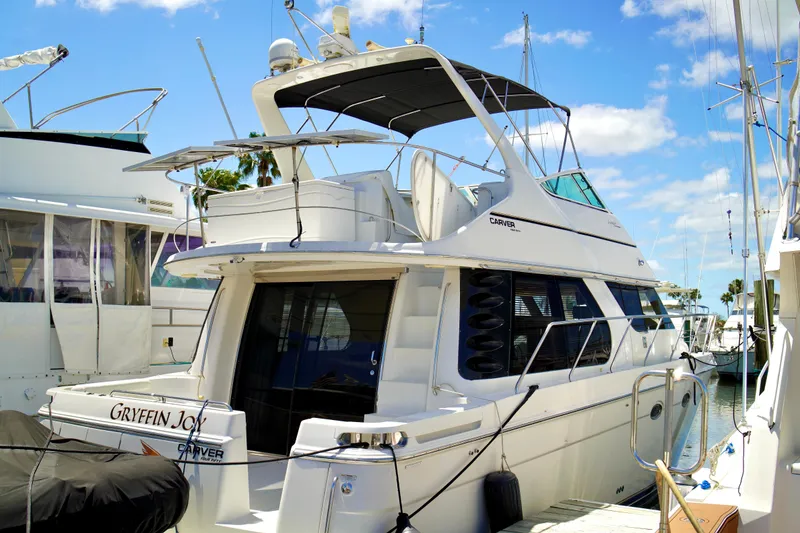 Slide: The Image of 1999 Carver 450 Voyager Pilothouse yacht docked at marina under clear blue sky. - 85