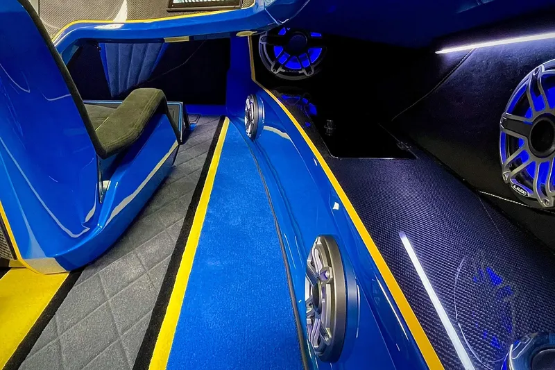 Slide: The Image of Interior of 2022 DCB M37 boat with blue and yellow accents, featuring speakers and seating. - 12