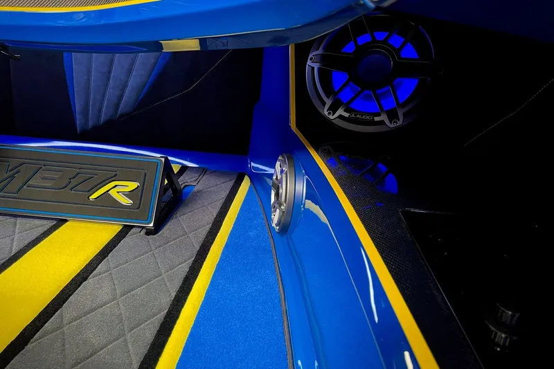 Slide: The Image of Interior of 2022 DCB M37 boat with vibrant blue and yellow accents, featuring JL Audio speaker. - 19