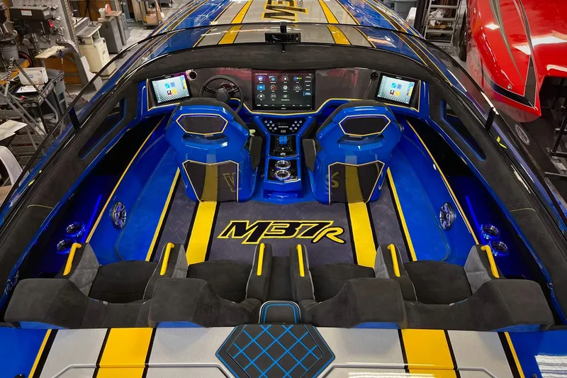 Slide: The Image of 2022 DCB M37 boat interior with blue and yellow accents, featuring advanced control panels. - 2