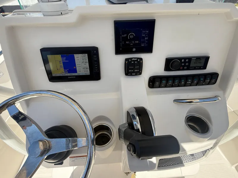 Slide: The Image of 2023 Sailfish 220 CC boat dashboard with steering wheel, navigation screens, and control panel. - 27