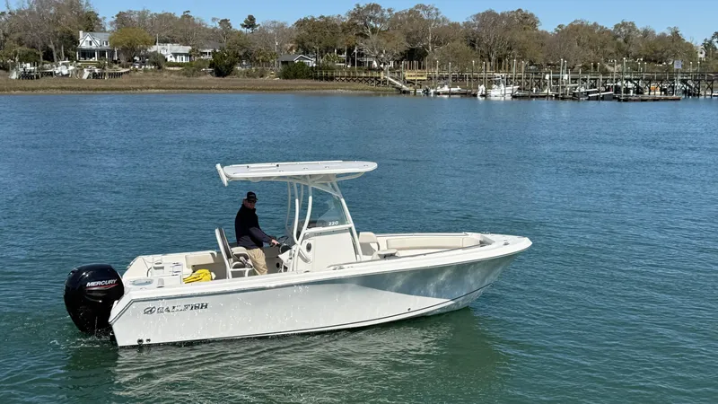 Slide: The Image of 2023 Sailfish 220 CC boat cruising on a calm river with scenic background. - 45