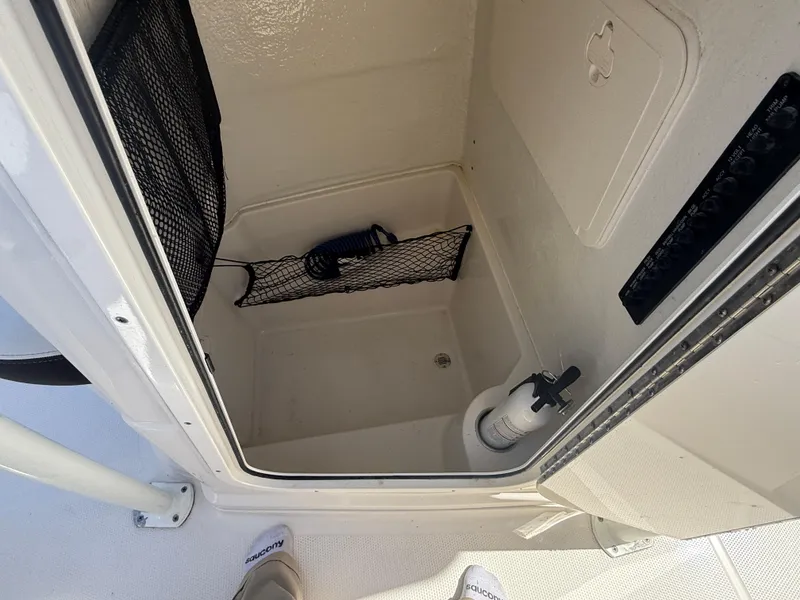 Slide: The Image of 2023 Sailfish 220 CC storage compartment with netting and fire extinguisher. - 7