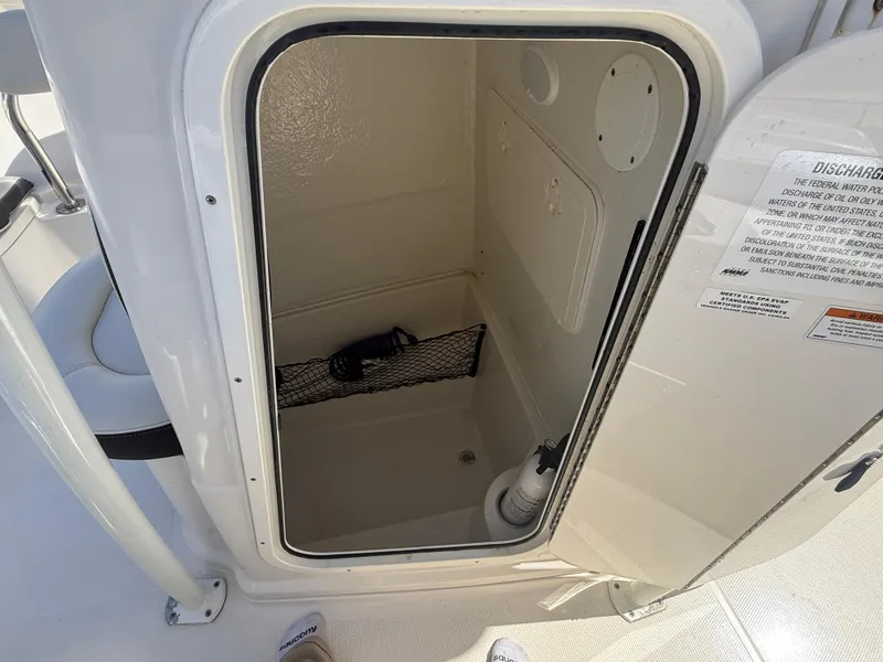 Slide: The Image of 2023 Sailfish 220 CC boat storage compartment with open door, showcasing interior space. - 8