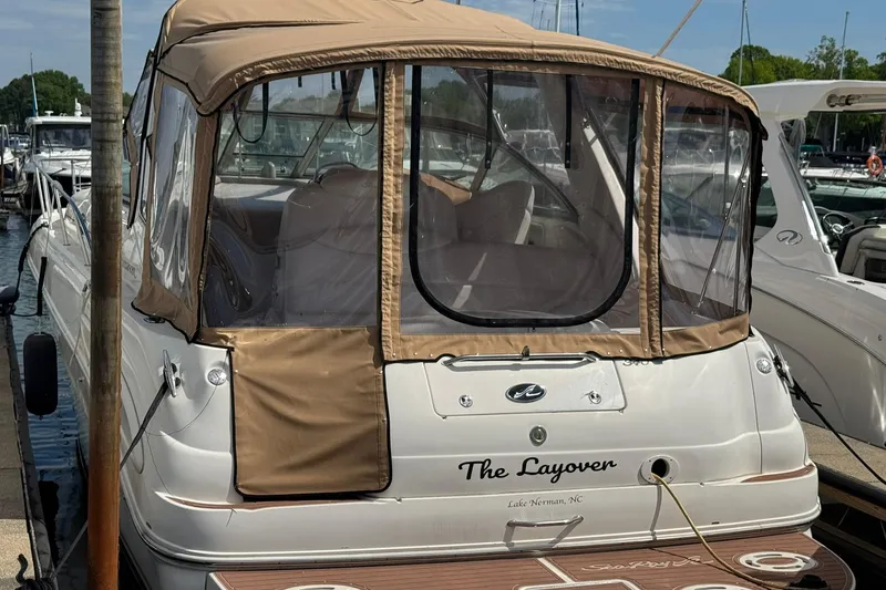 Slide: The Image of 2001 Sea Ray 340 Sundancer docked, featuring tan canopy and clear windows. - 2