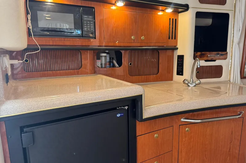 Slide: The Image of 2001 Sea Ray 340 Sundancer galley with wood cabinetry, microwave, and compact refrigerator. - 33