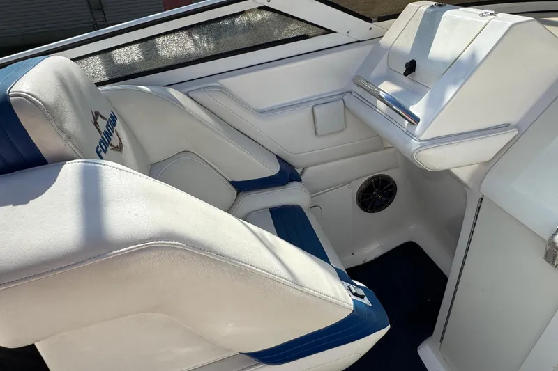 Slide: The Image of 2004 Fountain 27 Fever boat interior with white and blue seating, steering console, and speaker. - 23