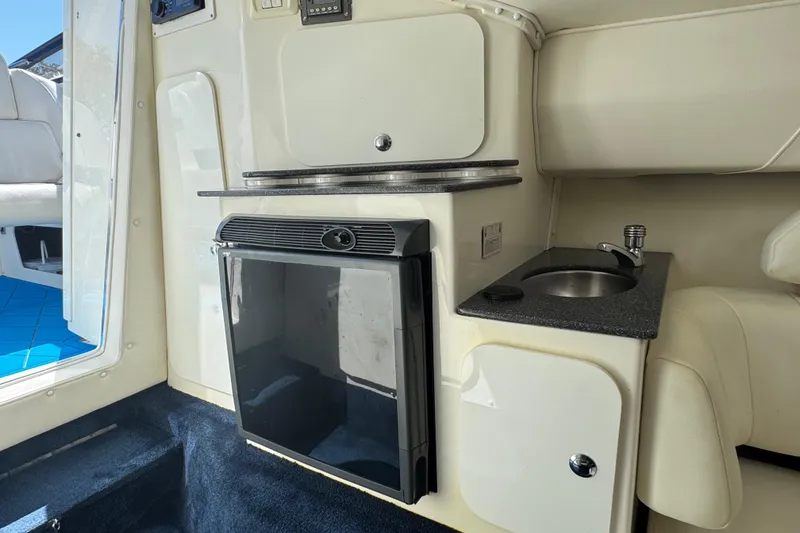 Slide: The Image of 2004 Fountain 35 Lightning boat interior with kitchenette, featuring a mini fridge and sink. - 23